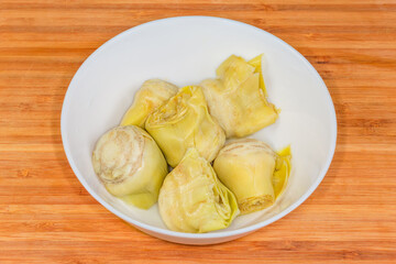 Canned green artichoke in white bowl on a cutting board