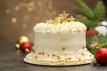 Delicious cake with Christmas decor on grey table against blurred lights, closeup