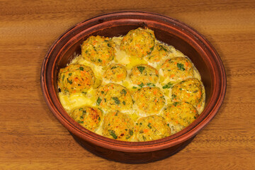Salmon patties baked in round clay roaster on wooden table