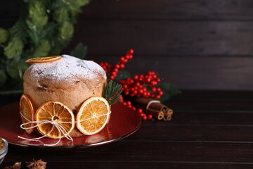 Christmas food. Delicious Panettone cake, spices and festive decor on wooden table, closeup. Space for text