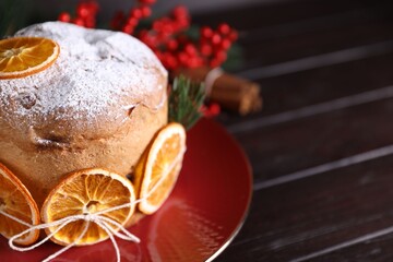 Christmas food. Delicious Panettone cake, spices and festive decor on wooden table, closeup. Space...