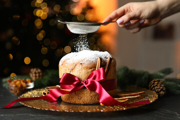 Christmas food. Woman sprinkling powdered sugar onto delicious Panettone cake, ingredients and...