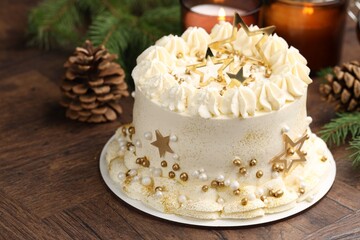 Delicious cake with Christmas decor and burning candles on wooden table, closeup