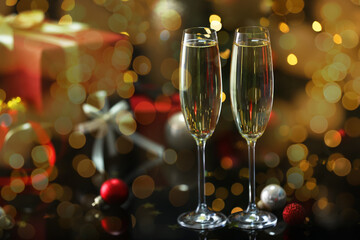 Sparkling wine in glasses and festive decor, bokeh lights. New Year greeting card