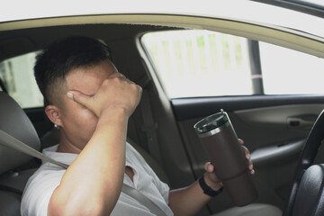 An asian male driver getting exhausted and feeling headache, wrist pain, neck ache, shoulder pain and backache, sitting inside his car, after driving car in traffic jam, causing stressed and anxiety.	