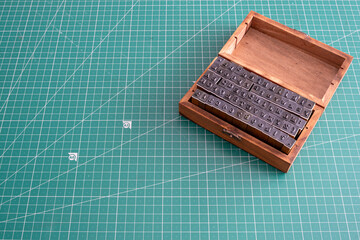 Wooden box with vintage rubber stamps on a green cutting mat, symbolizing creativity, handmade crafts, and artistic design tools in a minimal workspace