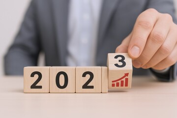 Naklejka premium Transition to 2023: Businessman Adding Last Block, Symbolizing Growth and Positive Business Outlook
