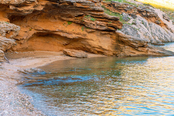 Serene coastal cave at rocky beach with turquoise waters and orange cliffs