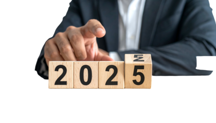 A person in a suit points to wooden blocks spelling out the year 2025
