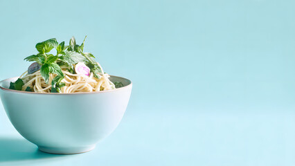 A simple close-up shot of a light-toned bowl containing noodles, vegetables, and herbs, set against a gentle pastel blue background. The clean and modern composition highlights simplicity, harmony, an