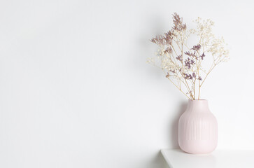 Elegant pink vase filled with delicate dried flowers stands on a white surface against a minimalist background, creating a serene and calming atmosphere for home decor