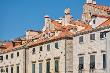 View of the red-tiled roofs and limestone facades of Dubrovniks Old Town, Croatia. A famous tourism destination set against a clear blue sky.