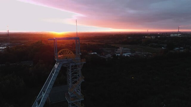 Oddalający lot ukazujący szyb i silne światło wschodzącego słońca prosto w obiektyw.
