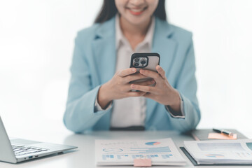 Fototapeta premium Asian businesswoman working with documents and computer at desk in office. Female office worker holding pen and using calculator while reading documents on desk.