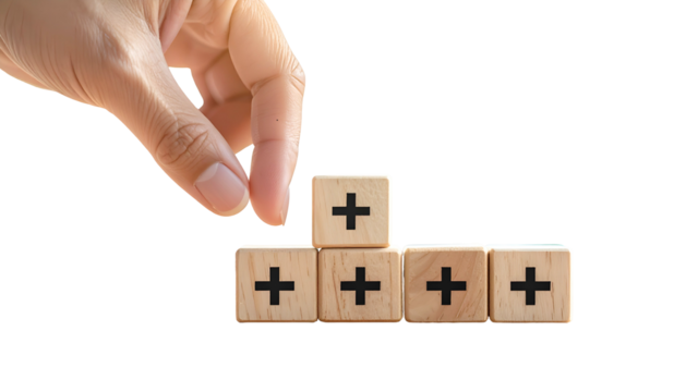 Hand arranging wooden cubes, each with a plus sign, against a black backdrop