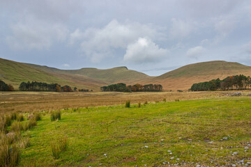 Obraz premium The serene beauty of Bannau Brycheiniog, featuring the majestic escarpment of Corn Du, Pen Y Fan, and Cribyn above the picturesque Taf Fechan river basin at the decommissioned Upper Neuadd Reservoir