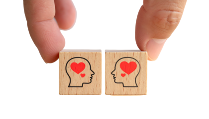 Hands hold wooden blocks with human head outlines & hearts, symbolizing connection