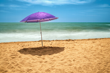 Lonely purple umbrella on Isla Canela beach captures daytime stillness