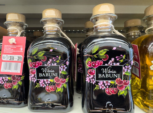 Klagenfurt, Austria - October 29, 2025: Wisnia Babuni cherry liqueur bottles displayed on a store shelf, showcasing vibrant floral designs and traditional branding in a retail environment