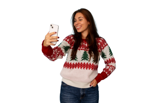 Young woman wearing ugly christmas sweater, smiling and taking selfie with smartphone, celebrating holiday season
