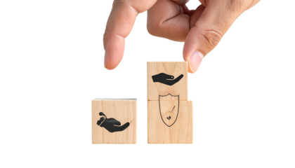 Hand placing a wooden block with a hand/shield icon atop another, both on a black background