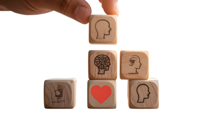 Hand placing a wooden cube with a head icon atop a pyramid of cubes with various mind and heart symbols