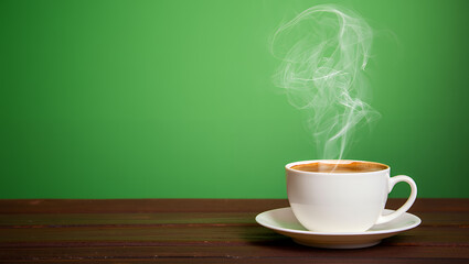A white ceramic coffee cup on a saucer with steam rising against a green background.
