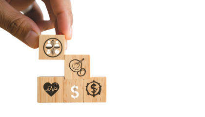 Hand stacking wooden blocks with symbols community, health, finances, and resources