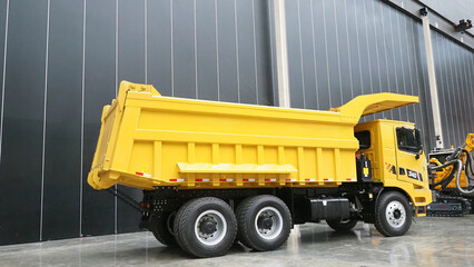A yellow dump truck is parked indoors on a concrete floor