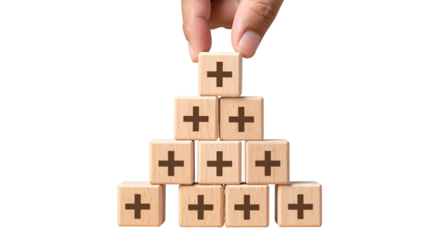 Hand placing top block of wooden blocks shaped like a pyramid with plus signs on black