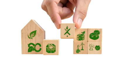 Hand placing a block symbolizing eco-friendly energy on a wooden house and icons