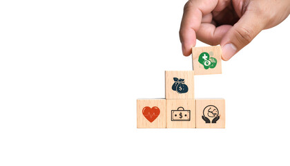 Hand placing health icon block atop a staircase of wealth, heart, and environment
