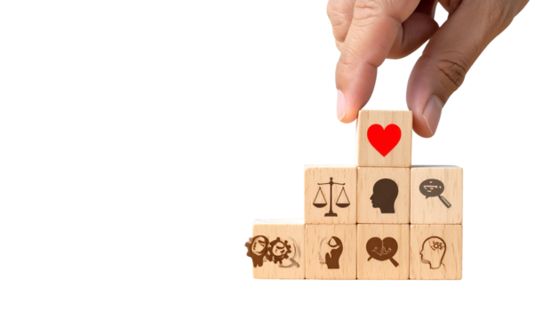 A hand placing a heart-symbol block atop a tiered stack of other symbol-etched blocks