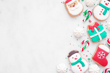 Colorful Christmas sweets side border on a white marble background with copy space. Overhead view....