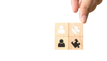 Hand places last block with puzzle piece onto a wooden cube with person icons on a black backdrop
