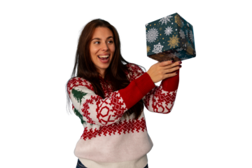 Woman feeling excited and surprised opening a holiday present, wearing a winter festive sweater during christmas celebration