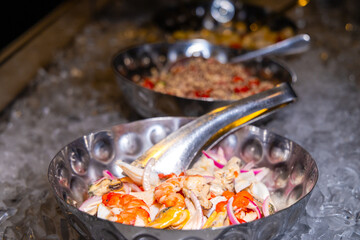 Fresh seafood salad with shrimp, mussels, onions in metal bowl on ice. Gourmet buffet presentation, luxury dining concept, vibrant colors.