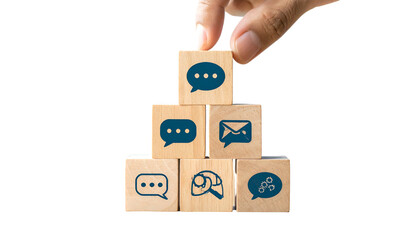 A hand places a speech bubble cube atop a wooden pyramid of communication icons