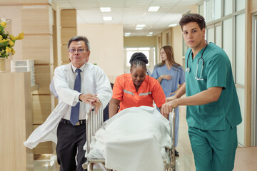 Obraz premium Medical team in hospital hallway transporting unconscious patient on stretcher in emergency situation with urgency and teamwork by asian male doctor, multiracial nurse, and young male assistant