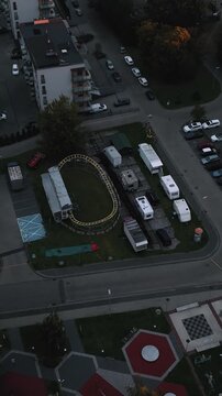 Niski przelot drona nad placem zabaw i karuzelą o poranku. Piękne pomarańczowe światło i bloki w tle.