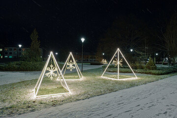 Minimalist Illuminated Christmas Pyramids with Snowflakes in Park on Dark Winter Night