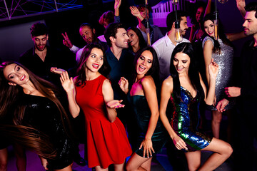 Lively group of friends and dancers enjoying a vibrant nightclub party dancing under neon lights in stylish dresses and suits