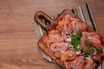 Chicken wings, marinated and laid out on a wooden platter, ready for cooking, grilling or baking, in a home kitchen, there are no people