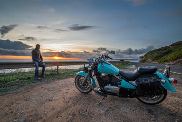 Fototapeta premium Man sitting on a guardrail by a classic motorcycle