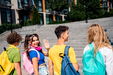 Young friends walking outdoors together, enjoying the sunny day in casual styles with backpacks, expressing happiness and joy.