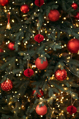 A close-up of a festive Christmas tree decorated with red ornaments, glowing fairy lights, and natural green pine needles.