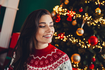 Bright festive smile beside christmas tree wearing red and white sweater in cozy home setting during holidays