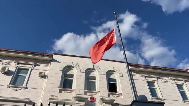 Chinese flag fluttering in the wind against blue sky and white building symbolizing patriotism national pride and identity in an urban setting