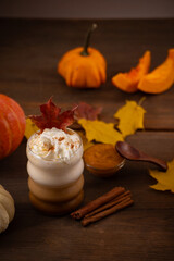 Cozy Autumn Pumpkin Spice Latte with Cinnamon Sticks, Pumpkin Butter, and Colorful Fall Leaves on Wooden Table