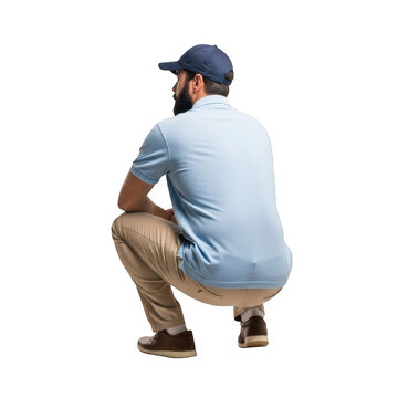 A man wearing a blue baseball cap and light blue short sleeve shirt with tan pants crouching down isolated on transparent background